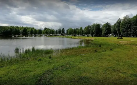 Vacker sjö vid Torsvikens camping med husbilar och träd.