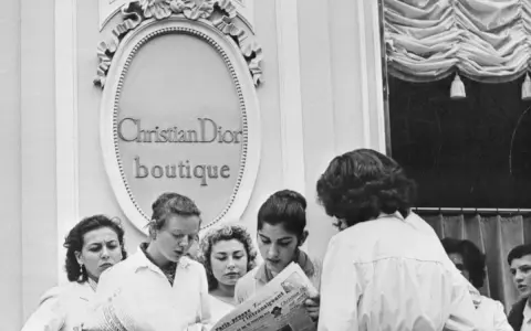 Donne leggono un giornale davanti alla boutique Christian Dior, dove nasce la moda.