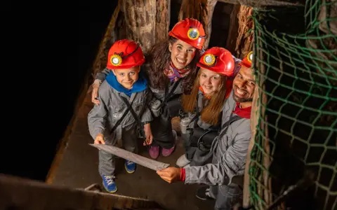 Rodzina w kaskach zwiedza kopalnię soli w Wieliczce. Dzieci z mapą w ręku, gotowe na przygodę!