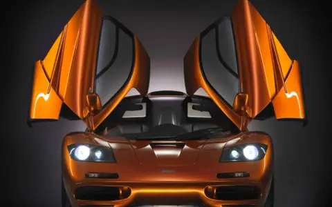 Orange McLaren F1 mit geöffneten Flügeltüren. Ein Traumauto, dessen McLaren F1 Preis unbezahlbar ist.