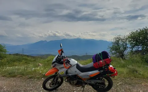 Motocykl gotowy na przygodę, z bagażami na wyprawę. Piękna grecja trasa z widokiem na góry.