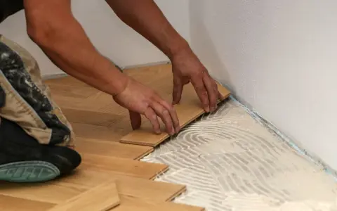 Manos colocando tablones de madera para un piso de parquet. Calculando el precio parquet piso 70m2.