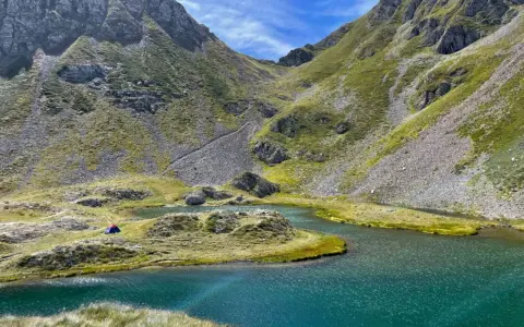 Un accampamento solitario ai laghetti di Ponteranica, tra montagne verdi e acque cristalline.