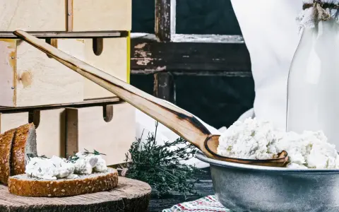 Fromage blanc frais, parfait pour une recette fromage blanc yaourtière. Servi sur du pain avec des herbes, à côté d'une bouteille de lait.