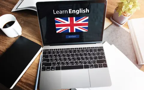 Laptop z napisem "Learn English" i flagą Wielkiej Brytanii. Obok kawa, notatnik i roślina. Idealne do nauki fce use of english.