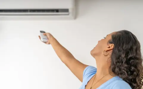 Donna con telecomando regola il condizionatore, la canalina condizionatore design si integra perfettamente.