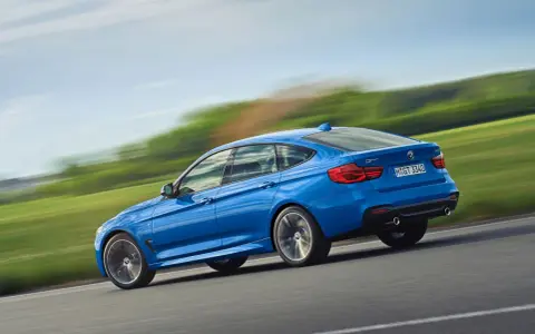 Niebieskie BMW 3 GT w ruchu, ukazujące jego sportowy profil. Warto rozważyć jego wady i zalety przed zakupem.