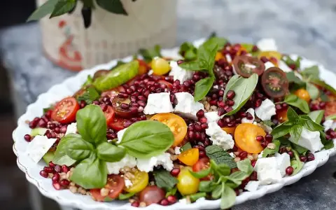 En färgglad sallad med granatäpple, tomater, fetaost och basilika, perfekt som sallad till grillat.