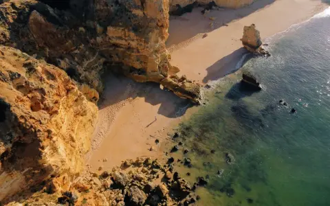 Malownicze klify i piaszczysta plaża w Portugalii. Morze o turkusowym odcieniu obmywa skaliste wybrzeże, tworząc idealne miejsce na spacer.