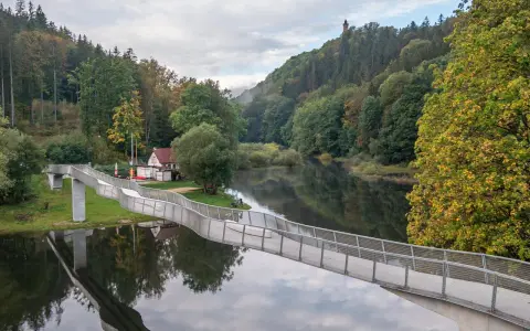 Idealna wycieczka na niedzielę na Dolny Śląsk: nowoczesny most nad spokojną rzeką, otoczony jesiennym lasem i wieżą widokową na wzgórzu.