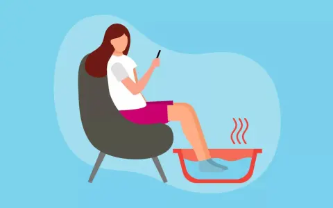 A woman relaxes in a chair, enjoying a soothing foot soak while scrolling on her phone.
