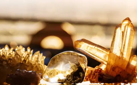 Un amas de cristaux dorés et un cristal poli, baignés de lumière, évoquent la beauté naturelle.