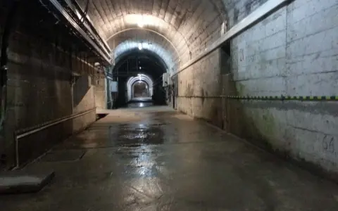 Wnętrze tunelu podczas zwiedzania elektrowni Solina. Mokra posadzka odbija światło lamp.