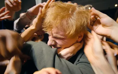 Ed Sheeran, mój azizam, otoczony przez tłum dłoni, które chcą go dotknąć.