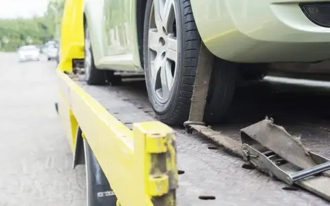 Czy komornik może zająć samochód osobie niepełnosprawnej? Auto na lawecie, zabezpieczone pasami.