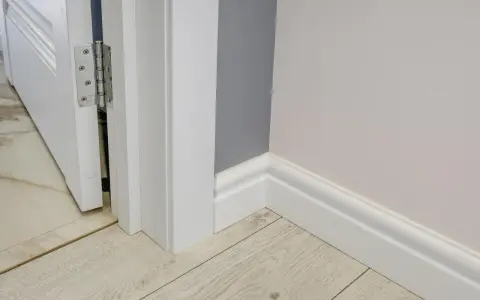 Nymålade vita snickerier runt en dörröppning och längs väggen ger ett fräscht intryck.