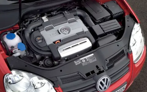 Silnik 1.4 TSI Twincharger w czerwonym Volkswagenie. Widoczne elementy układu dolotowego i chłodzenia.