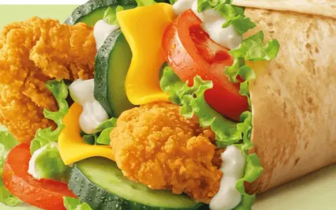 McWrap Bekon Deluxe: chrupiący kurczak, bekon, ser, warzywa i sos w tortilli. Pyszny i sycący, idealny na szybki posiłek.
