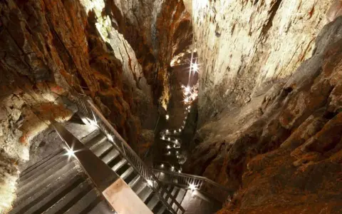 Schody prowadzą w głąb skalnej groty, oświetlonej licznymi lampkami. Ta grotta gigante zaprasza do odkrywania jej tajemnic.