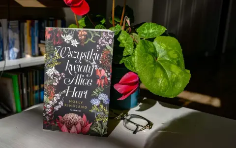 Okładka książki "Wszystkie kwiaty Alice Hart" z motywem roślinnym, obok cyklamen i okulary.