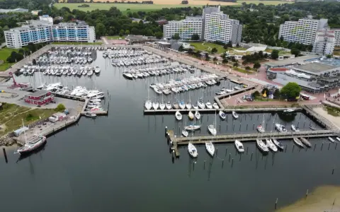 Viele Segelboote und Yachten liegen im dampfenden Hafen von Damp. Moderne Gebäude säumen die Küste.