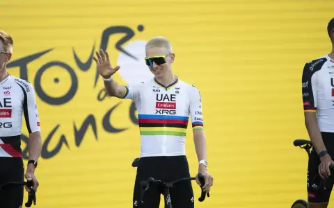 Radfahrer mit bunten Trikotfarben der Tour de France winkt fröhlich.