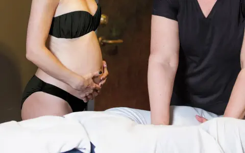 Gravid kvinna får massage på mage och rygg. En massagepistol kan vara ett skonsamt alternativ för gravida.