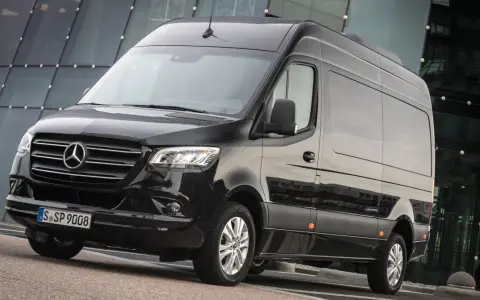 Czarny bus 3.5 tony, lśniący na tle nowoczesnego budynku. Idealny do transportu osób lub towarów.