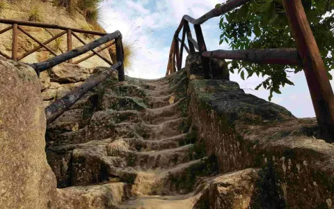 Antica scala in pietra scavata nella roccia, con ringhiera in legno, che conduce verso l'alto, evocando un'esplorazione in una grotta in Calabria.