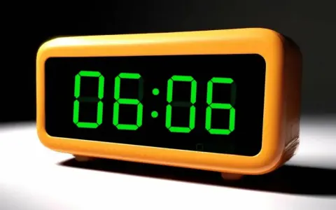 Pomarańczowy budzik cyfrowy pokazuje godzinę 06:06. Idealny czas na rozpoczęcie dnia lub na przerwę.