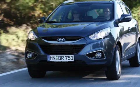 Dunkelgrauer Hyundai ix35 fährt auf einer Straße. Fahrer und Beifahrerin sind zu sehen. Mögliche Hyundai ix35 Probleme sind hier nicht ersichtlich.