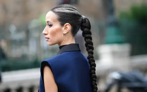 Eine Frau mit einem dicken, geflochtenen Zopf und Highlights. So kann man haare einfach stylen für einen eleganten Look.