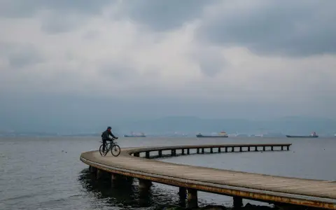Rowerzysta przemierza malownicze trasy rowerowe nad morzem, podziwiając spokojną taflę wody i statki na horyzoncie.