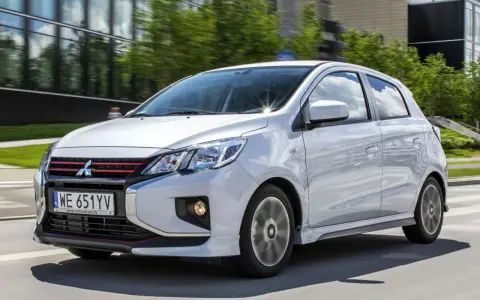 Srebrny Mitsubishi Space Star z czerwonymi akcentami na grillu i zderzaku jedzie po drodze.