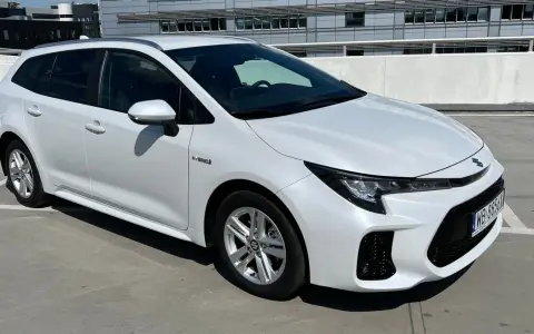 Biały Suzuki Swace Hybrid na parkingu. Elegancki kombi z nowoczesnym designem, gotowy na każdą podróż.