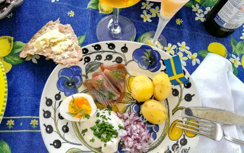 En härlig sillunch midsommar med färskpotatis, ägg, gräddfil och rödlök. En svensk flagga vajar glatt.
