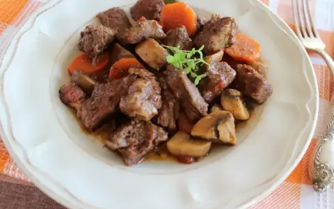 Bœuf bourguignon: duszona wołowina z marchewką i pieczarkami, podana na talerzu.