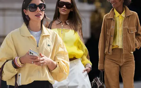 Drei Frauen in modischen Outfits. Die vordere trägt eine gelbe Jacke, die mittlere ein gelbes Top. Welche Farbe passt zu Gelb? Braun, wie die Jacke der rechten Frau, ist eine tolle Wahl.