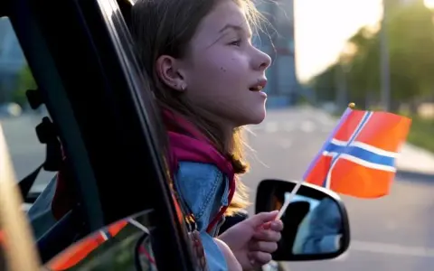 Dziewczynka z norweską flagą w ręku, wyjeżdża z kraju. Sprowadzenie auta z Norwegii to początek nowej przygody.