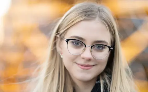 Uśmiechnięta blondynka w okularach, z rozmyciem tła. Idealna ogniskowa do portretu, podkreślająca oczy.