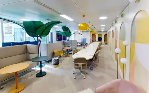 Espace de travail moderne et coloré, ce **flex office** offre des zones de réunion, des canapés confortables et des plantes décoratives pour un environnement stimulant.