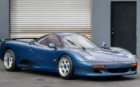 Blauer Jaguar XJR-15 Sportwagen mit auffälligem Heckspoiler und glänzenden Felgen, bereit für die Rennstrecke.