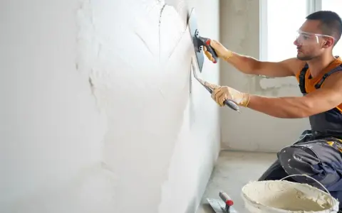 Artisan appliquant un enduit chaux sable intérieur à la taloche. Le mur prend forme, prêt pour une finition naturelle et saine.