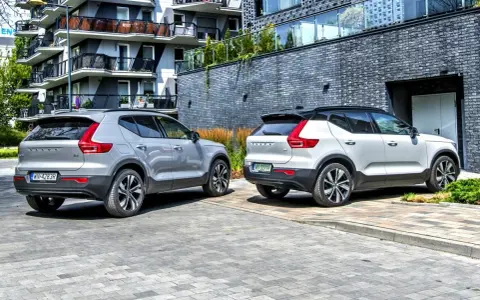 Dwa modele Volvo XC40, jeden srebrny, drugi biały, zaparkowane przed nowoczesnym budynkiem.