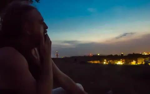 Mężczyzna zamyślony patrzy na nocne miasto. Odeszłam, ale tęsknię za tym widokiem.