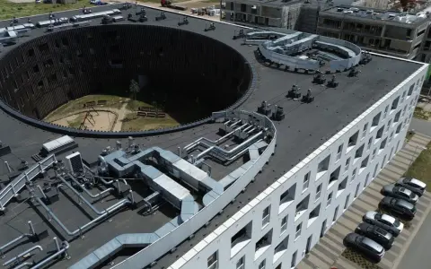 Nowoczesne budynki we Wrocławiu, z charakterystycznym okrągłym dziedzińcem i skomplikowaną instalacją wentylacyjną na dachu. Żerniki Wrocławskie w pełnej krasie.