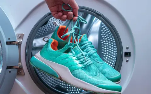 Türkisfarbene Laufschuhe werden vor dem Waschen in der Waschmaschine gehalten.
