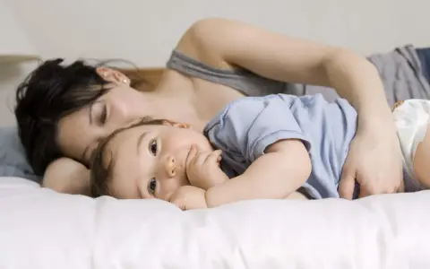 Mama tuli roczne dziecko do snu, przytulając je blisko.