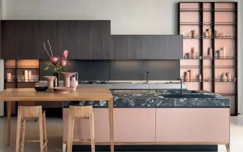 Cucina moderna con isola rosa cipria e piano in pietra scura, pensili in legno scuro. Ottimi abbinamenti colori cucine moderne.