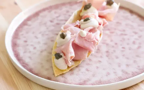 Delizioso antipasto con pane carasau, prosciutto cotto, crema e capperi. Un'idea per ricette veloci e gustose.